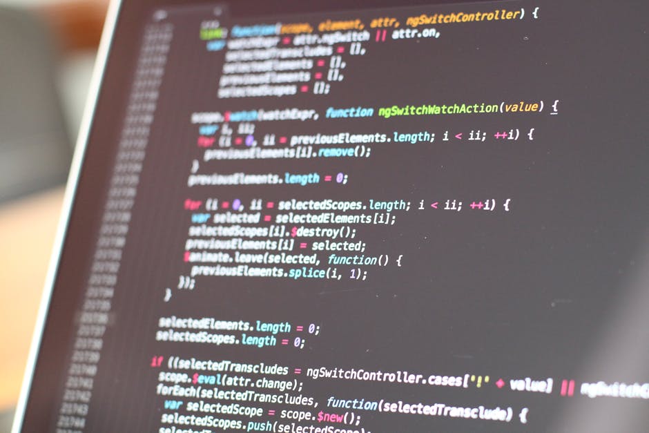 A close-up of a computer screen displaying lines of colorful code in a text editor, with code syntax highlighting in shades of blue, pink, green, and white on a dark background. The screen is slightly